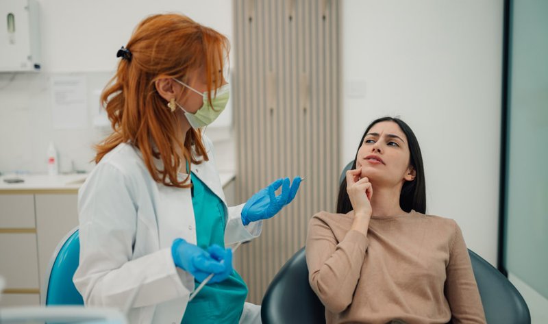 Dentist discussing tooth pain treatment plan with patient