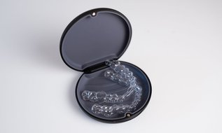 Clear Invisalign aligners lying in a black open case, representing orthodontic treatment options in Ontario