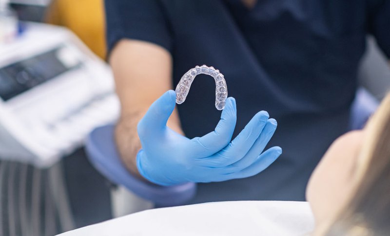 Professional orthodontist demonstrating innovative, clear Invisalign aligners to a patient at a dental clinic in Ontario