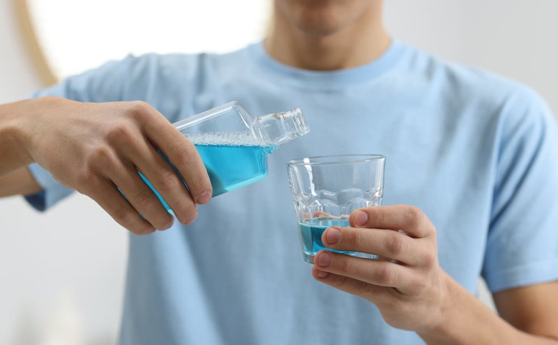 Hand pouring hydrogen peroxide into a medicine cup for dilution