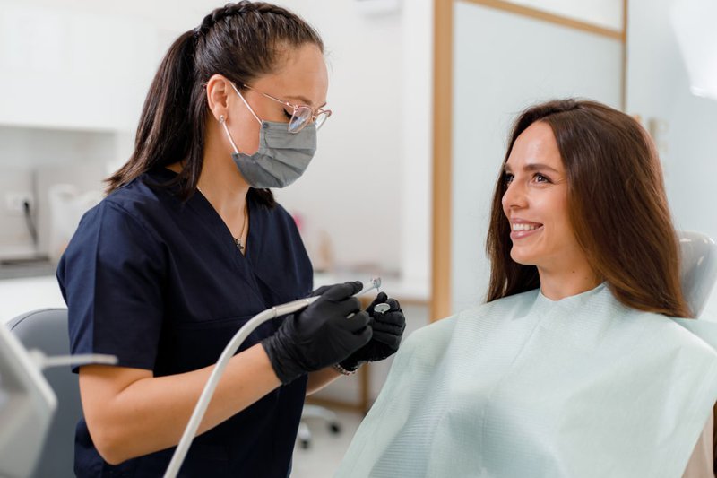 Hygienist removing tartar using an ultrasonic scaler during dental cleaning