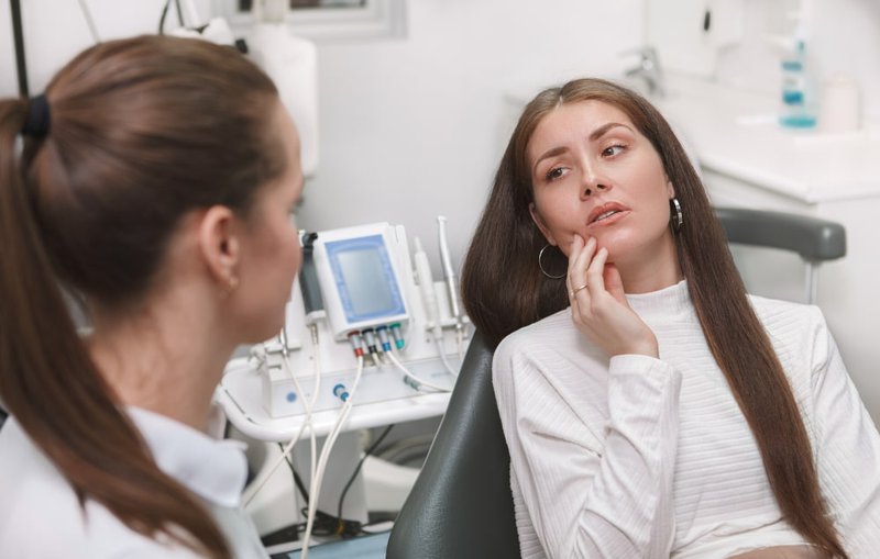 Female patient receiving dental evaluation for recurring tooth pain