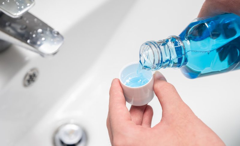 Young man swishing hydrogen peroxide mouthwash indoors